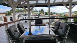 Un espacio exterior techado con mesa y sillas, con vista a un barrio residencial.