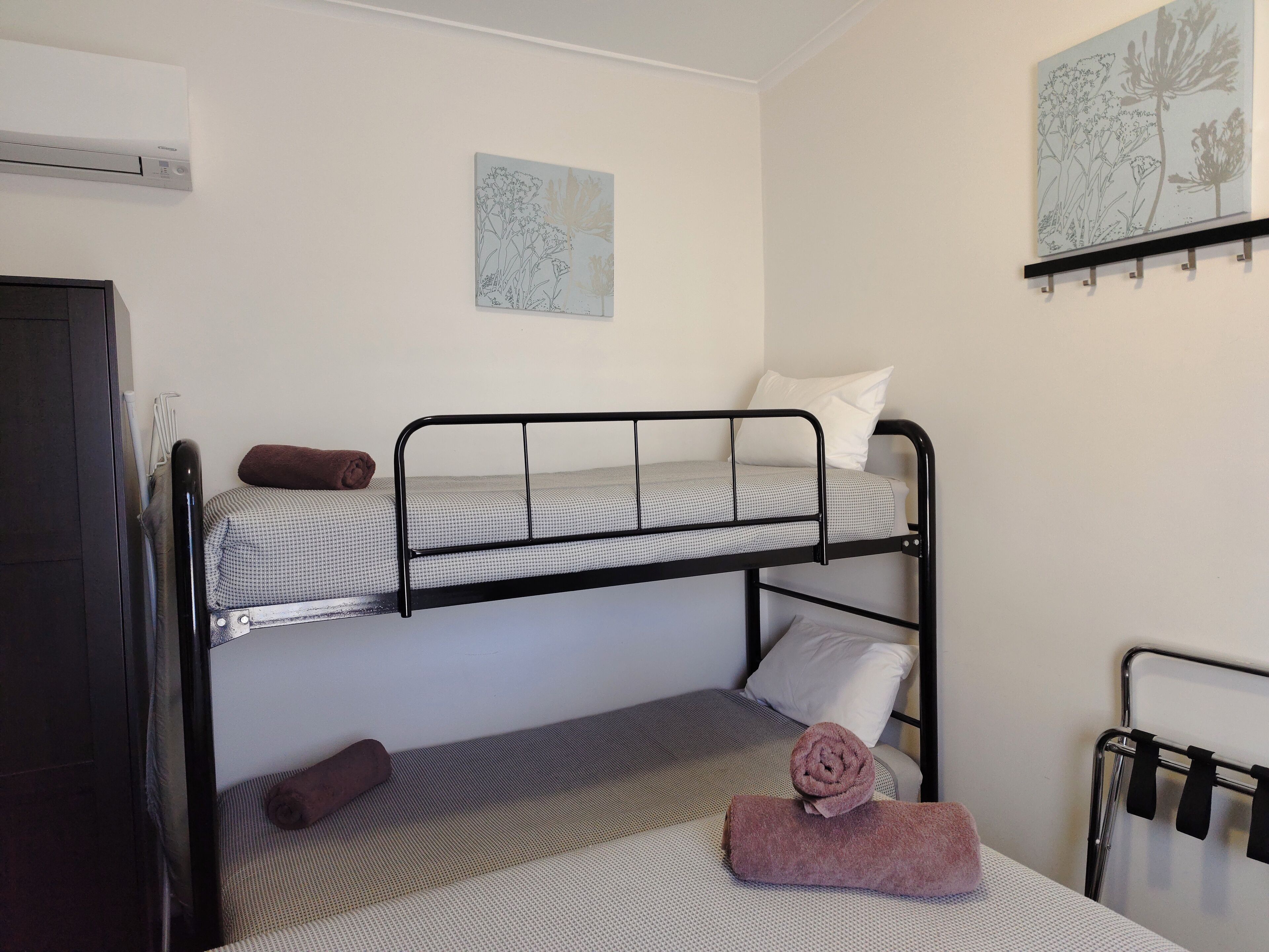 A bunk bed room with a towel on the lower bunk, a towel on the floor, and a wall-mounted towel rack.