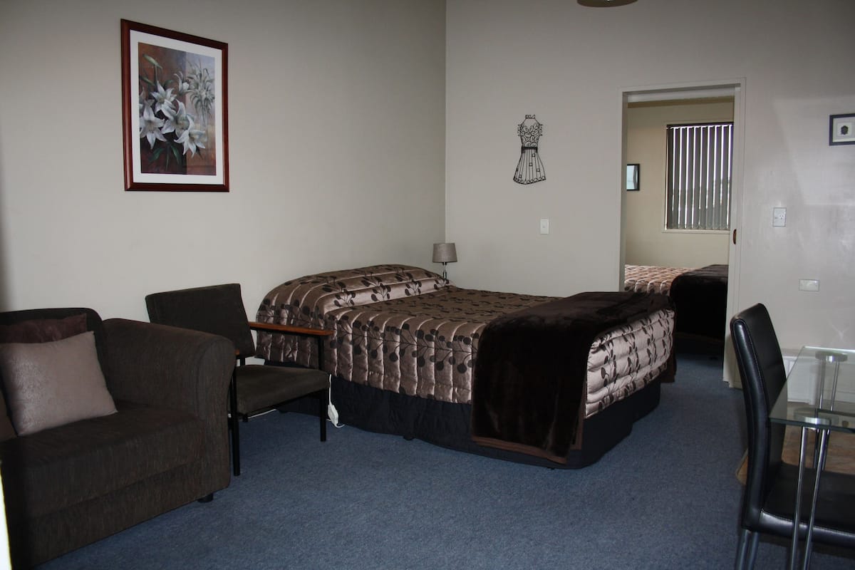 A room with a bed, a chair, a couch, and a small table.