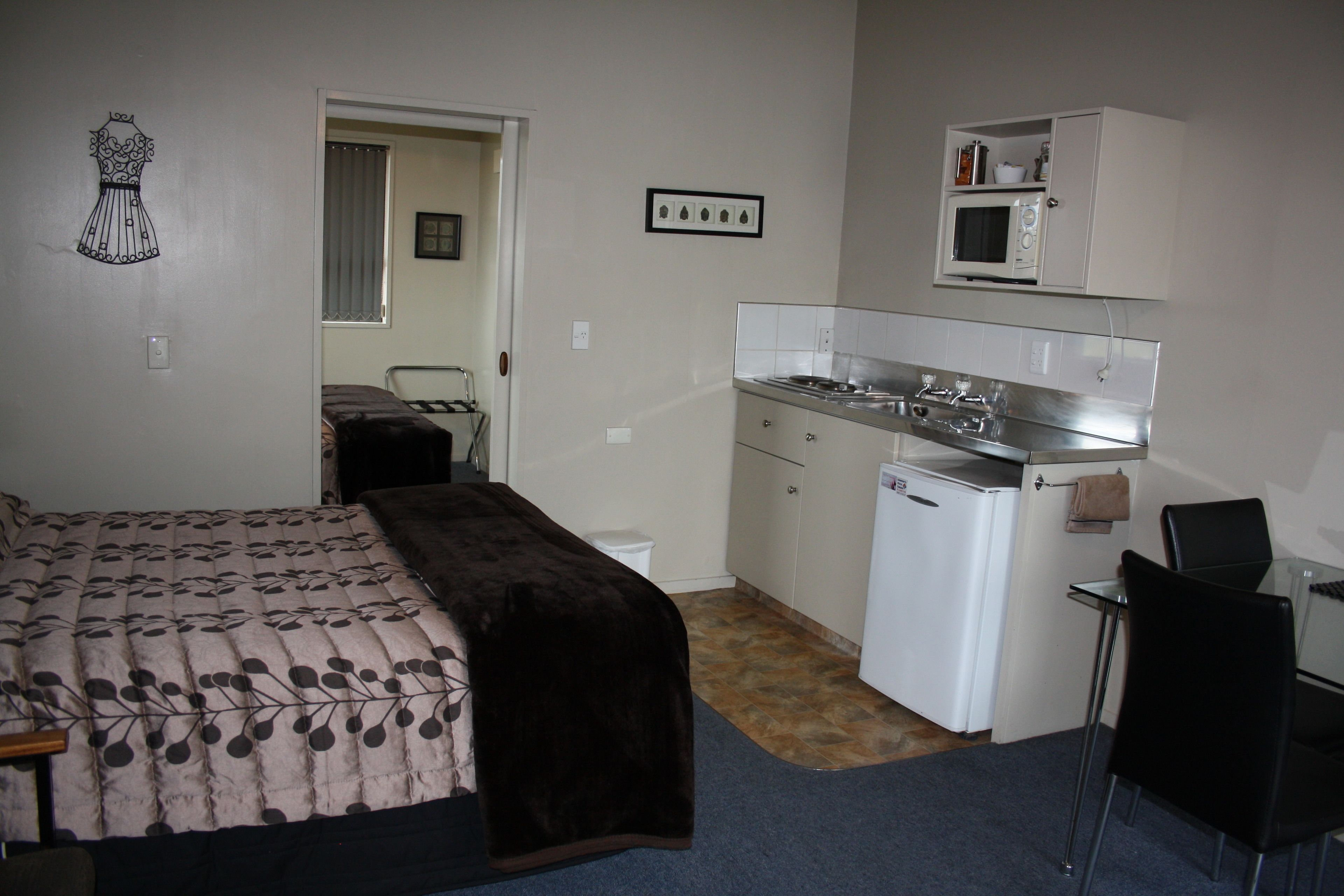 A compact room with a bed, a small kitchenette, and a separate dining area.