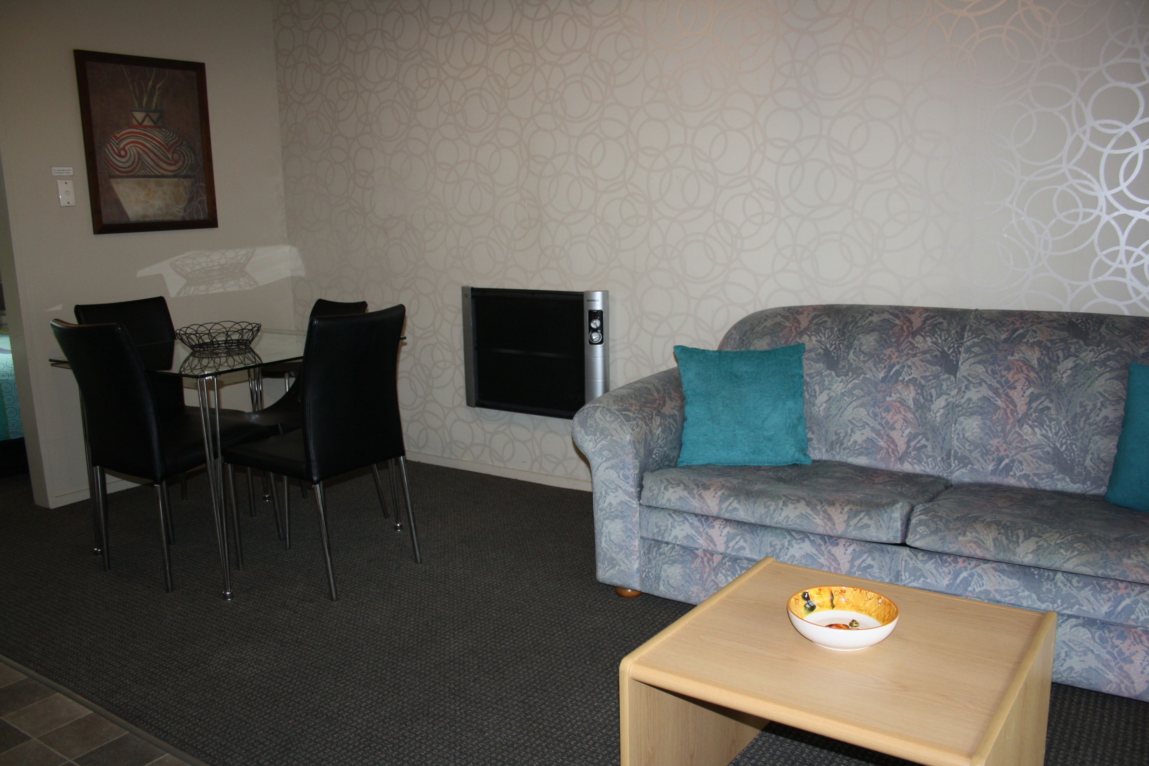 A living room with a sofa, a coffee table, a TV, and a dining area with chairs and a table.