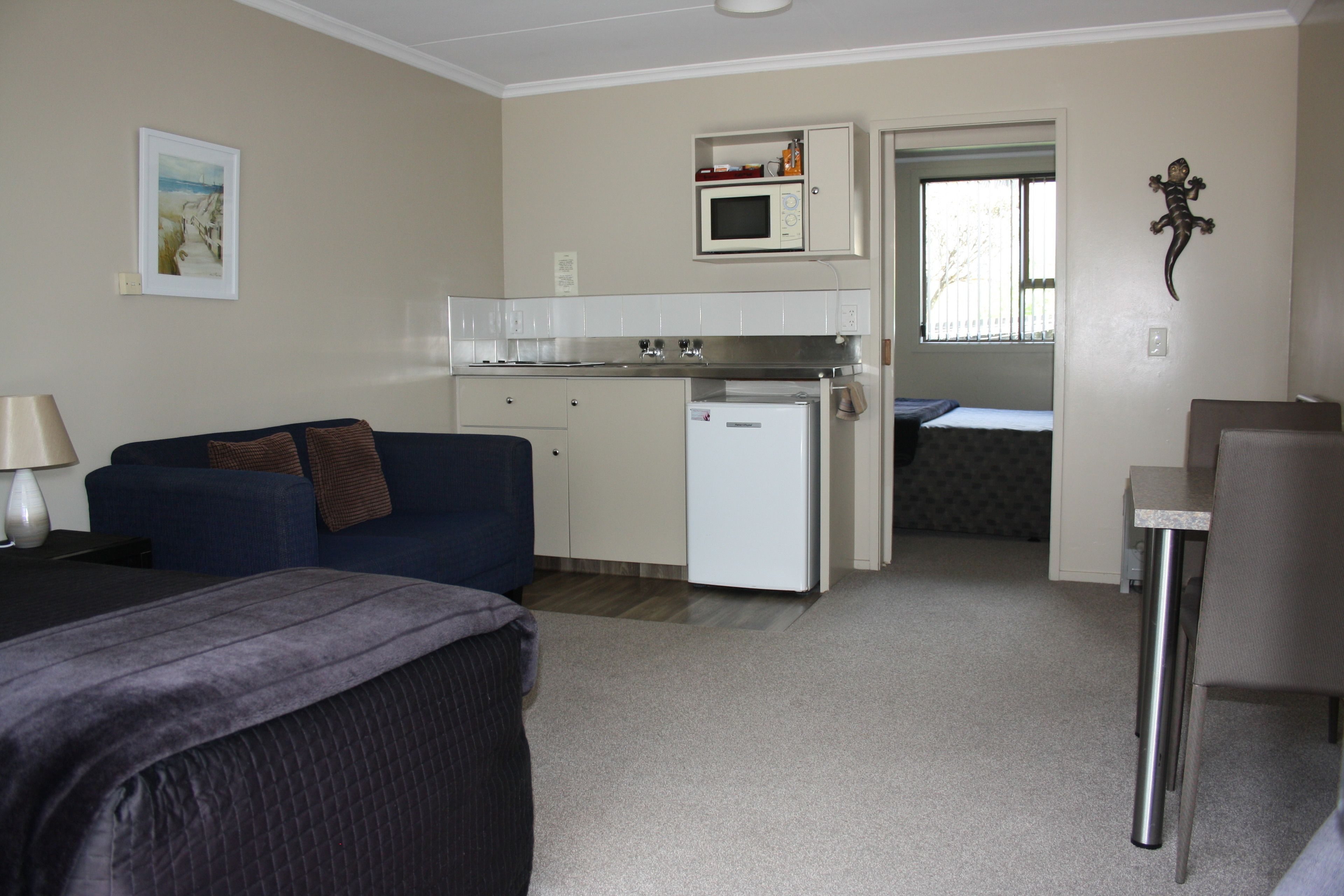 A compact room with a kitchenette, a bed, a sofa, and a small table.