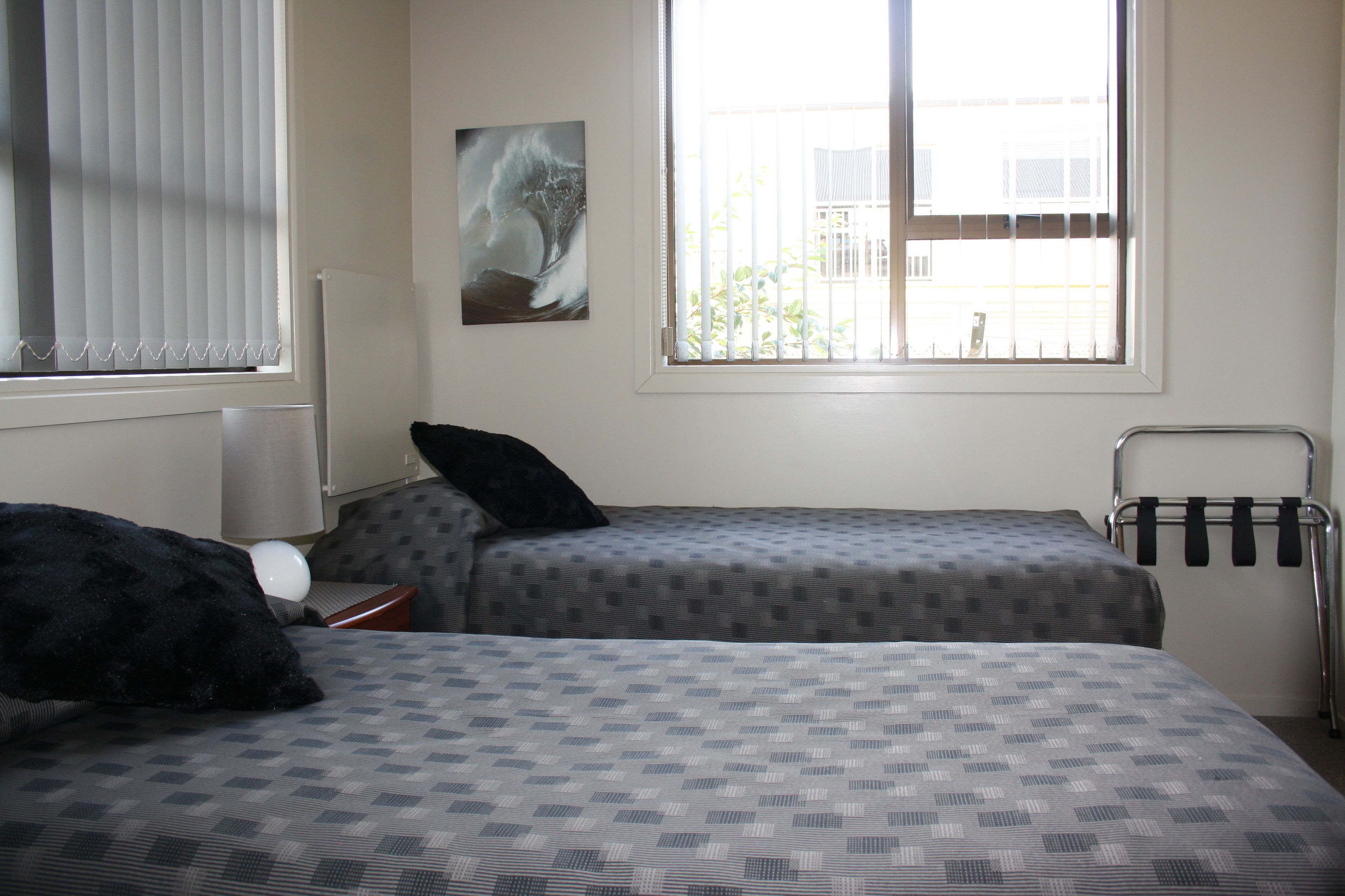 Une chambre avec deux lits, un radiateur, une fenêtre avec des stores et un porte-serviettes.
