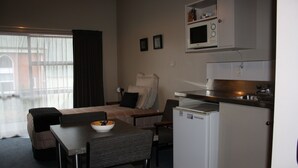 A compact living space with a kitchenette, a dining area, and a seating area with a sofa and chairs.