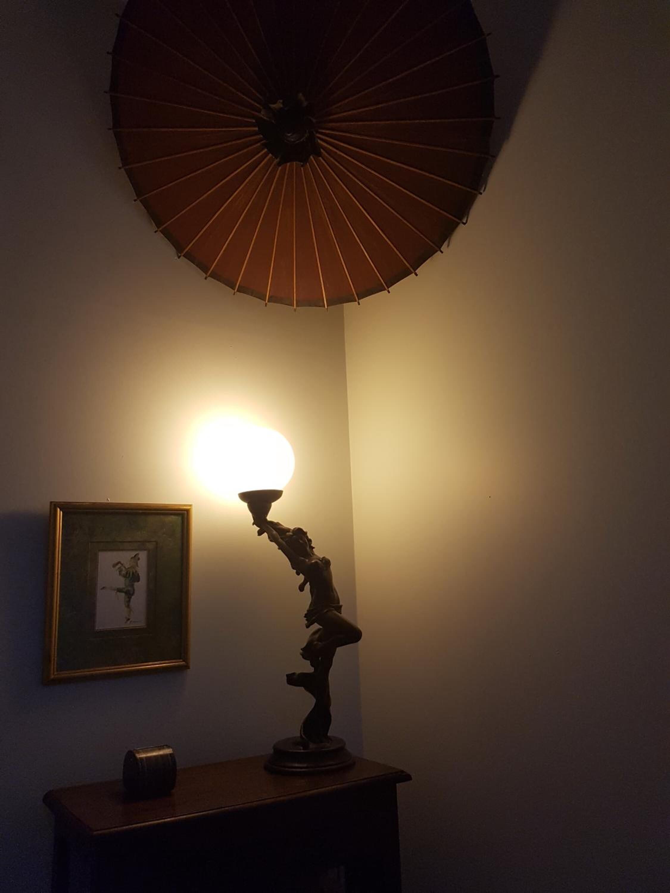 A room with a table lamp casting a warm glow, a framed picture on the wall, and a ceiling fan.