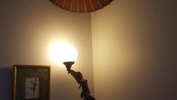 A room with a table lamp casting a warm glow, a framed picture on the wall, and a ceiling fan.