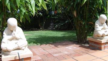 Zwei Stein-Buddha-Statuen in einem Garten mit einem Kachelweg.