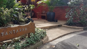 A sign reading "TANTARRA" in front of a building with a red roof and large potted plants. - Tantarra Guest House (Warners Bay)