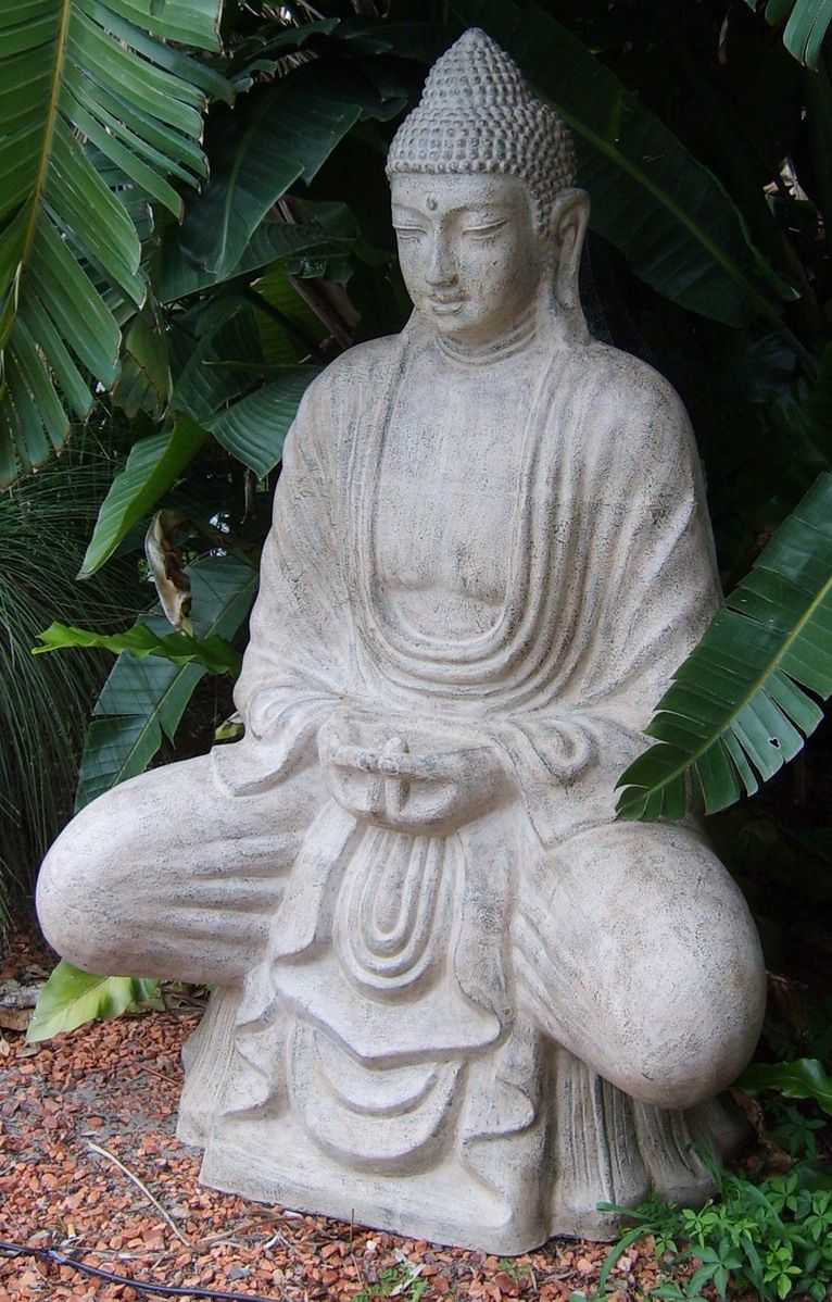 Una estatua de Buda de piedra en un jardín.