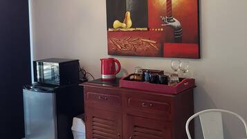 A compact kitchen area with a refrigerator, a coffee maker, and a cabinet.