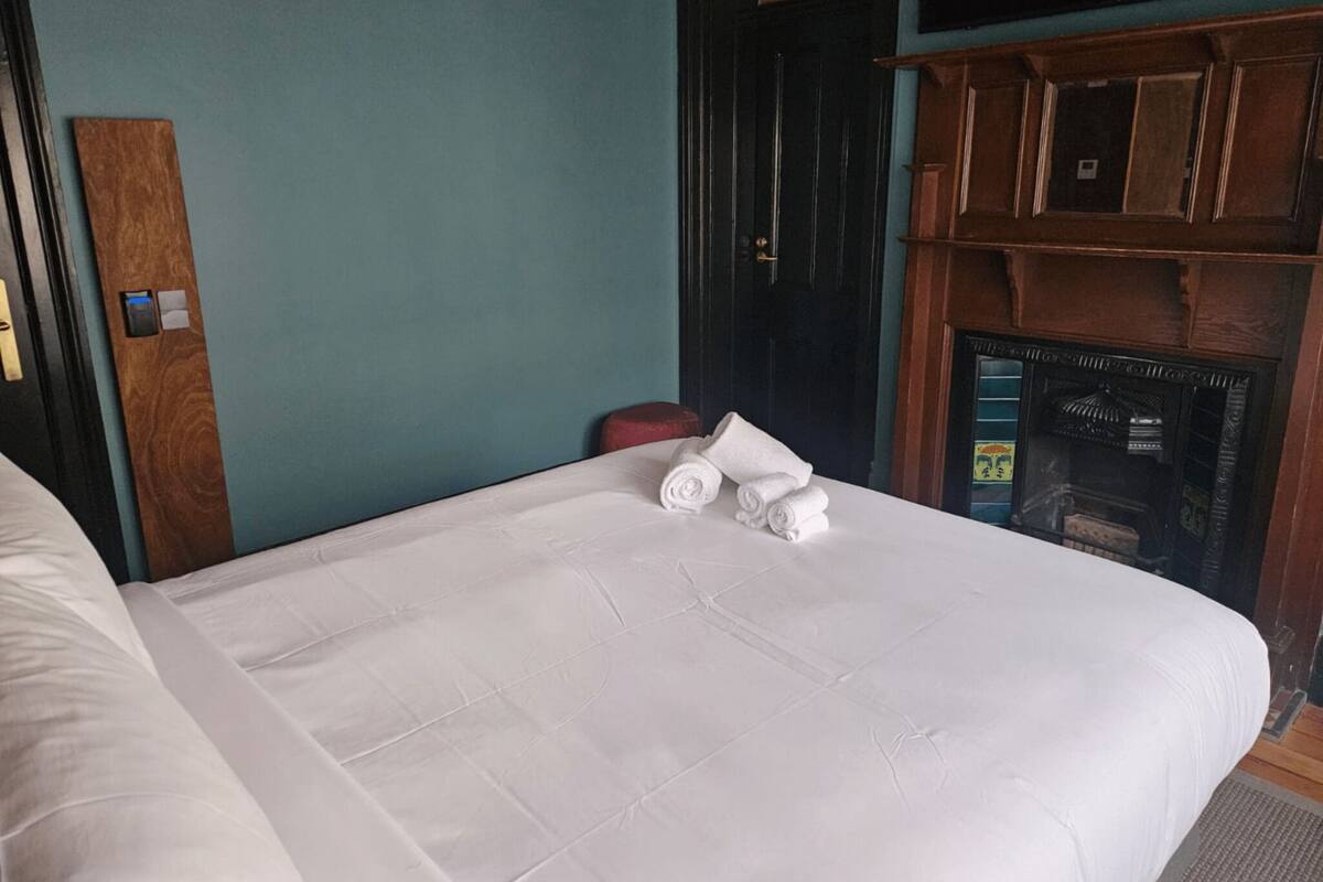 A hotel room with a bed, a wooden door, and a fireplace.
