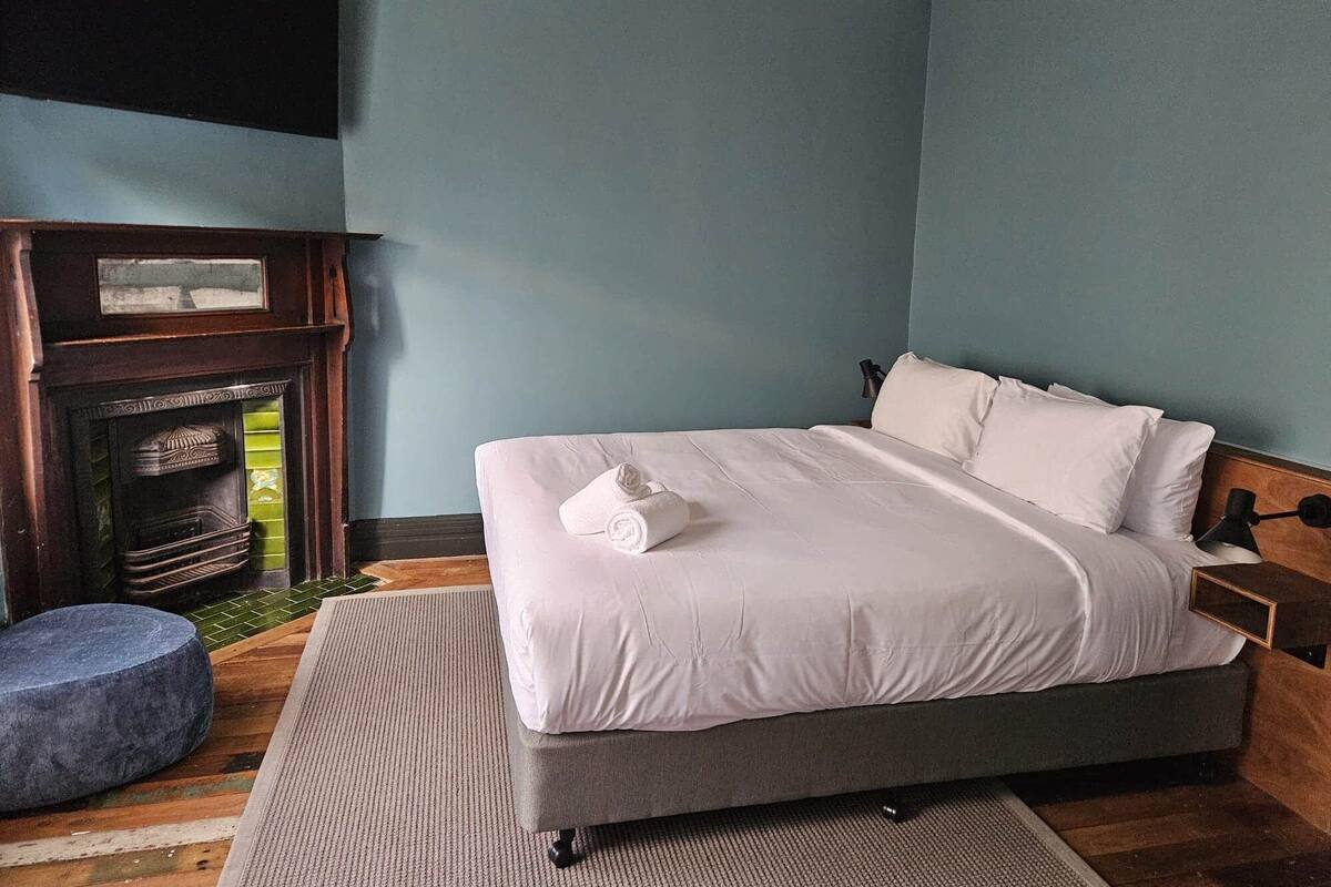 A bedroom with a bed, a fireplace, and a nightstand.
