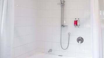 A modern bathroom with a white bathtub, a shower, and a toilet.