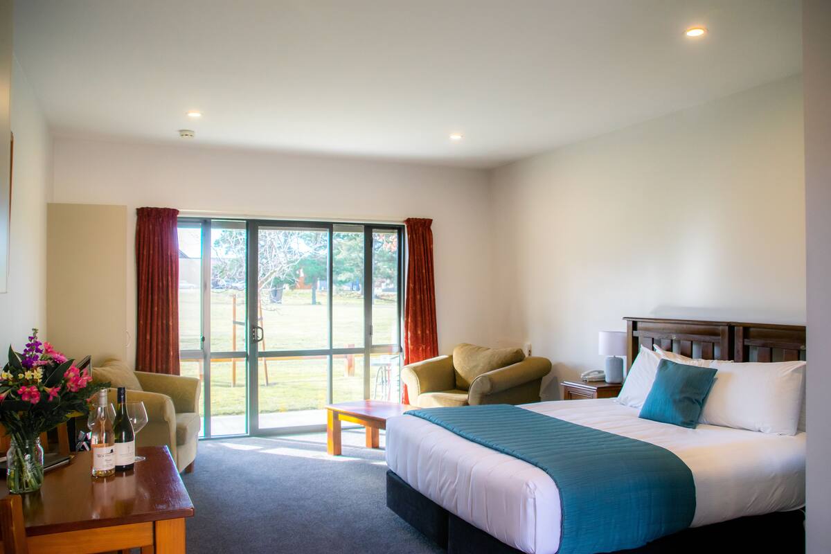 A hotel room with a bed, a desk, a chair, and a view of the outdoors.