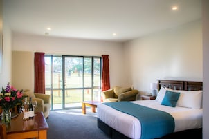 Quarto de hotel com cama, escrivaninha, cadeira e vista para o exterior.