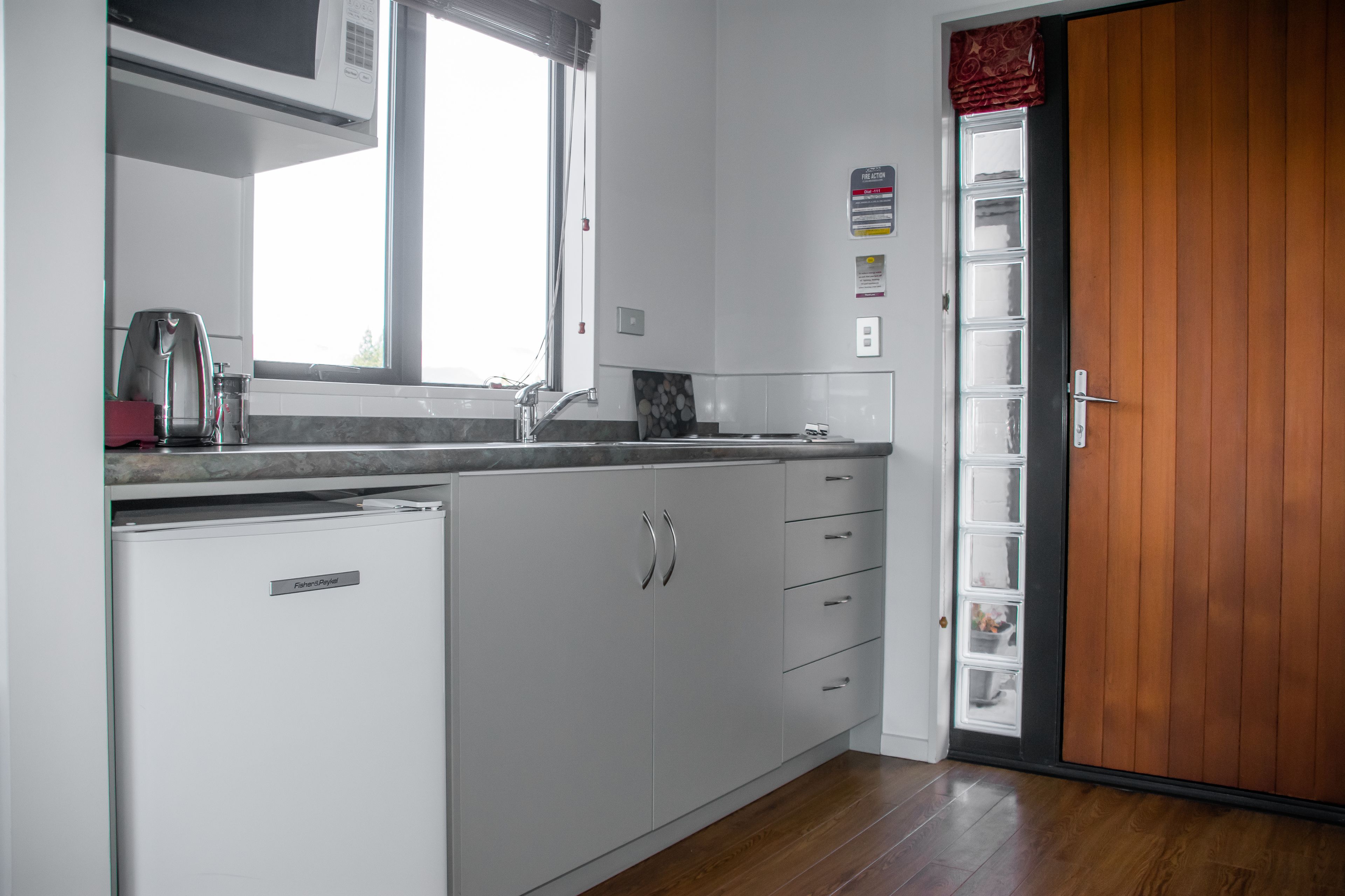 A kitchen with white cabinets, a microwave, and a window.
