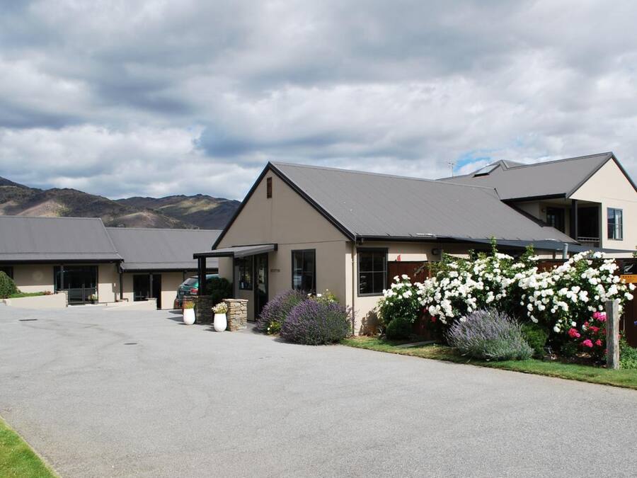 A modern hotel with a covered driveway and a landscaped garden with white flowers.