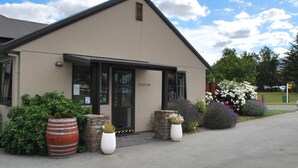 A modern building with a beige exterior, a black roof, and a glass entrance. - Carrick Lodge Motel (Cromwell)