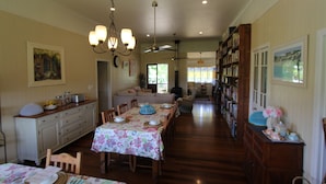 Un comedor amplio con una larga mesa dispuesta para una comida, una sala de estar acogedora con un sofá y una estantería llena de libros.