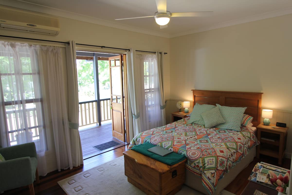 A bedroom with a bed, a nightstand, a chair, and a wooden bench.