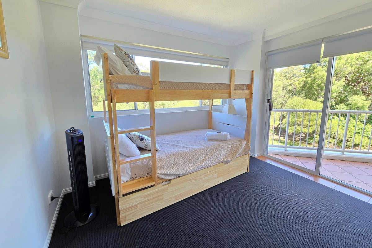 A bunk bed room with a view of greenery outside.