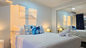 A hotel room with a large bed, a bedside table, a mirror, and a wall-mounted air conditioner. - Fairways Golf & Beach Retreat (Woorim)