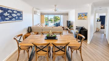 A modern living room with a dining area, a sofa set, a TV, and artwork on the walls.