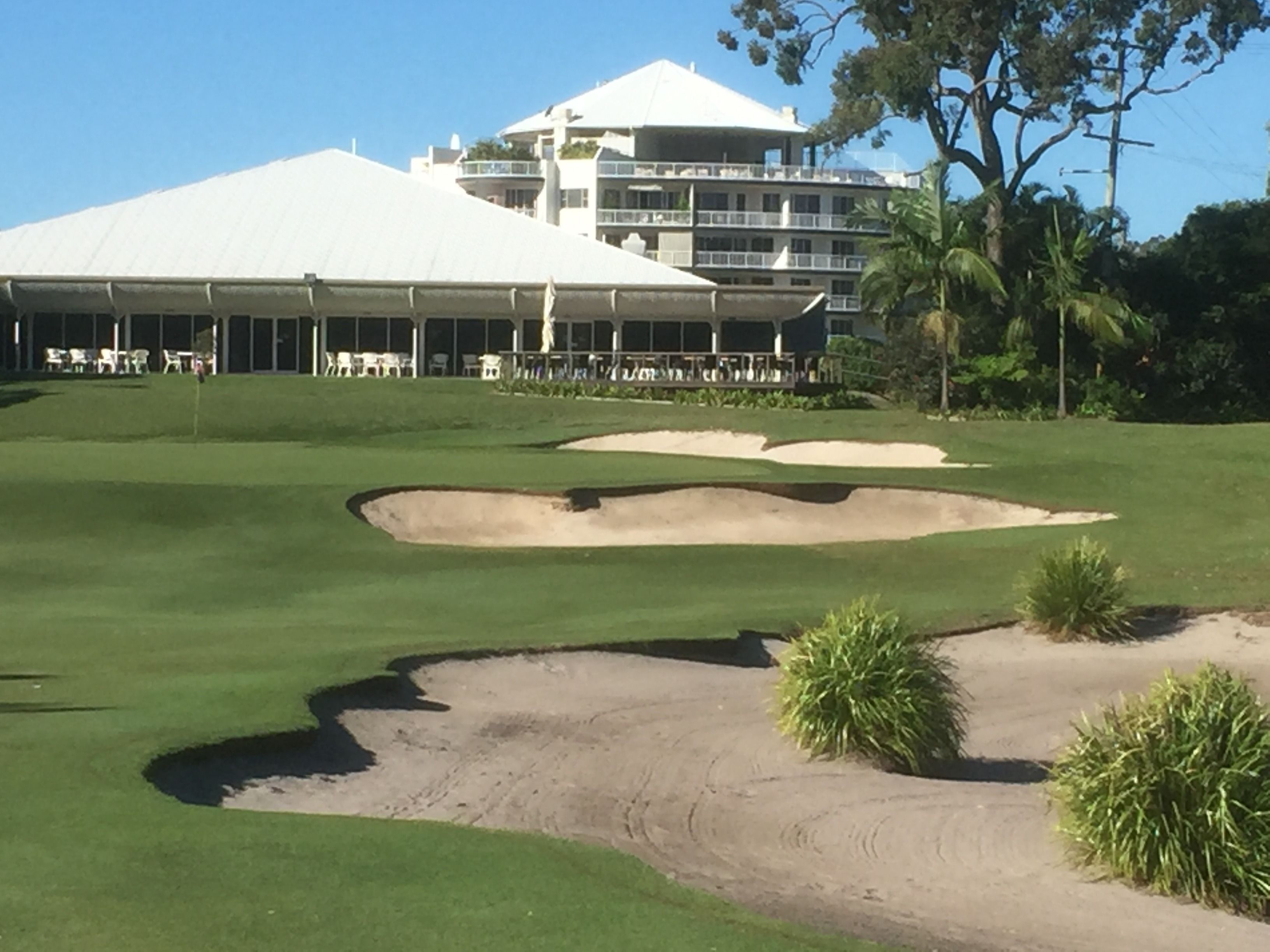 Un campo da golf con bunker e un edificio con tetto bianco sullo sfondo.