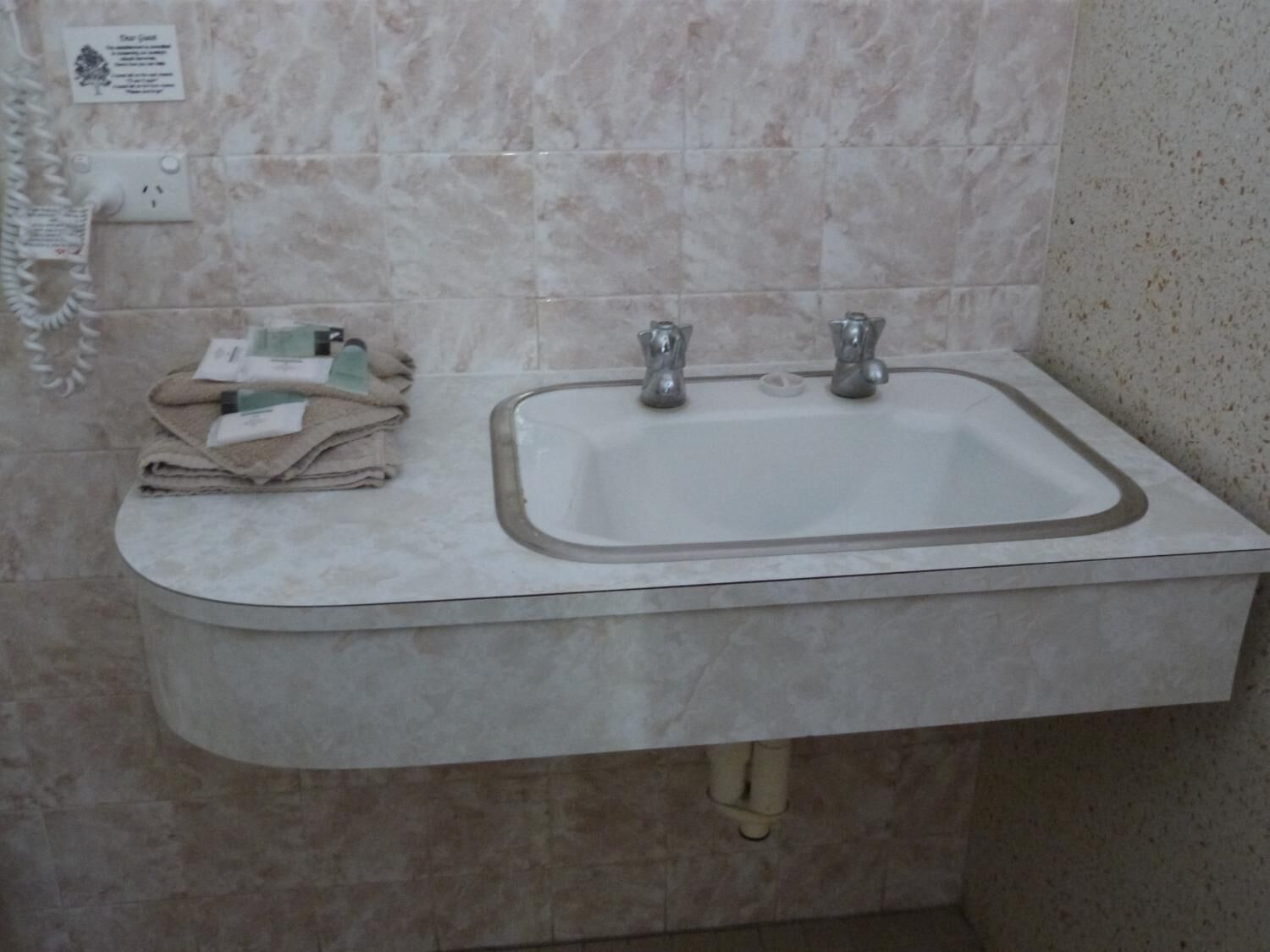 A bathroom sink with a marble countertop, a towel, and a soap dispenser.