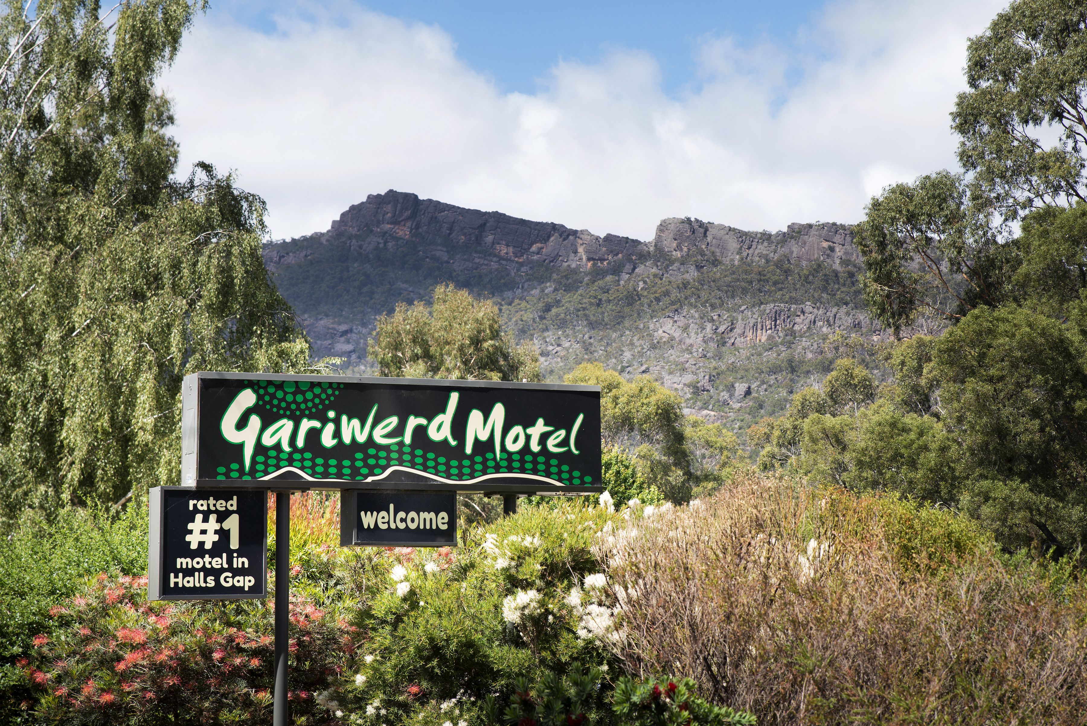 A sign for the Gariwerd Motel with a view of a mountainous landscape in the background.