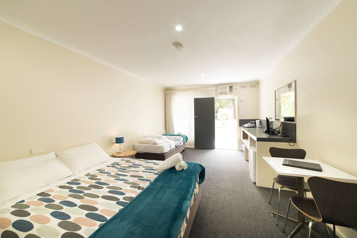 Una habitación de hotel con cama, escritorio, silla y kitchenette.
