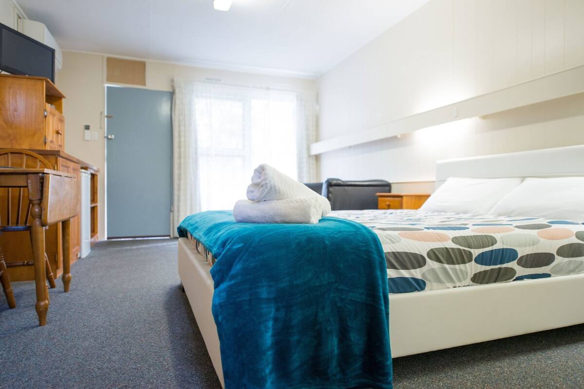 Una habitación de hotel con una cama, un escritorio y una puerta.
