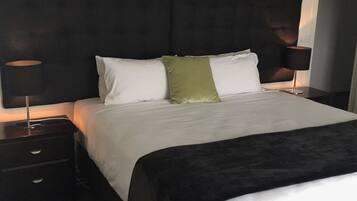 A hotel room with a large bed, two bedside tables, and a dark headboard.