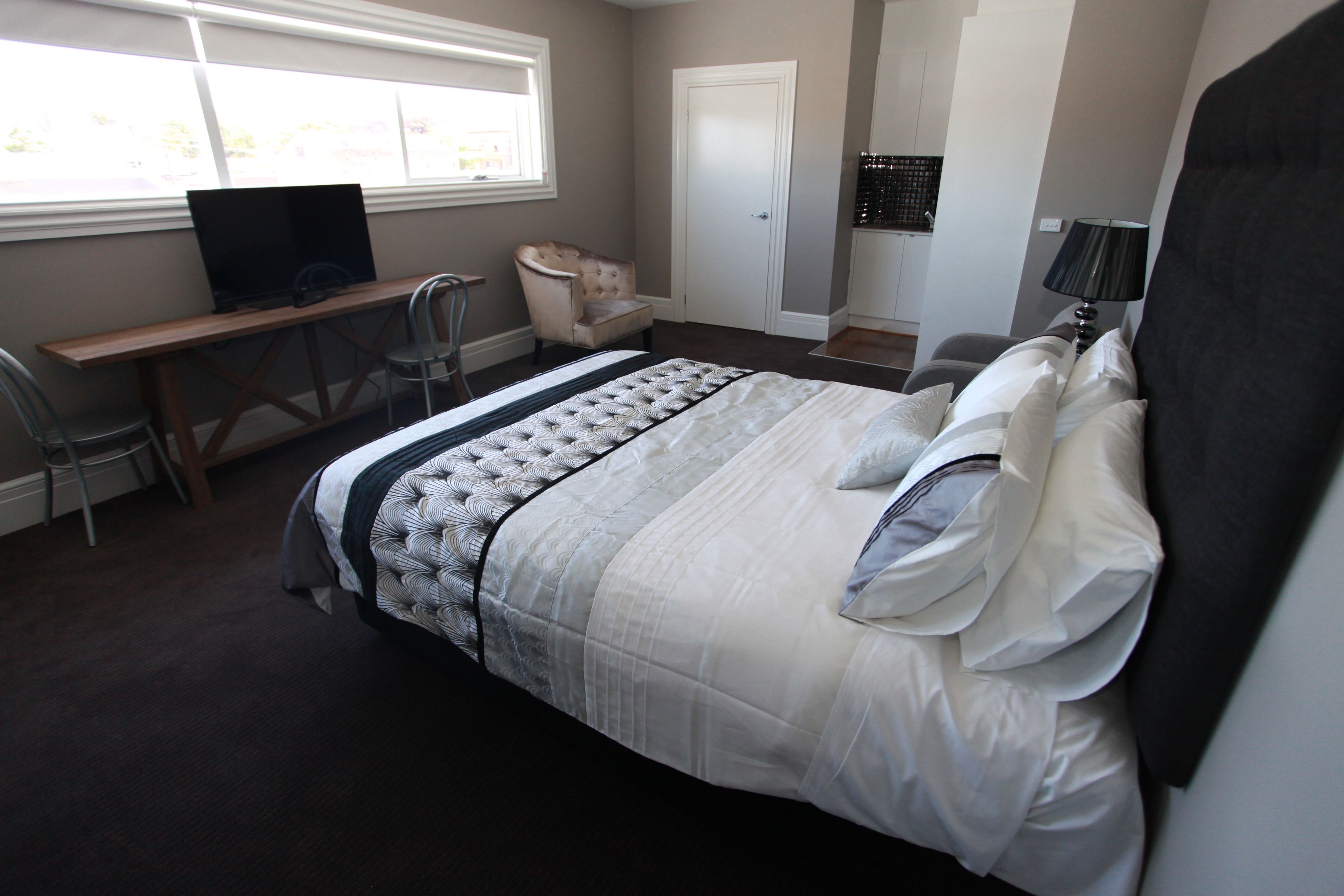 A bedroom with a bed, a desk, a chair, and a television.