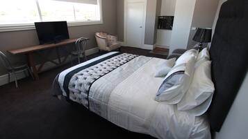 A bedroom with a bed, a desk, a chair, and a television.
