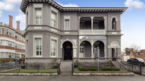 Un edificio gris con puerta principal negra, un balcón y un letrero que dice "Ballarat Premier Apartments".