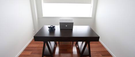 A room with a dark wooden table, a laptop, and a small electronic device on it.