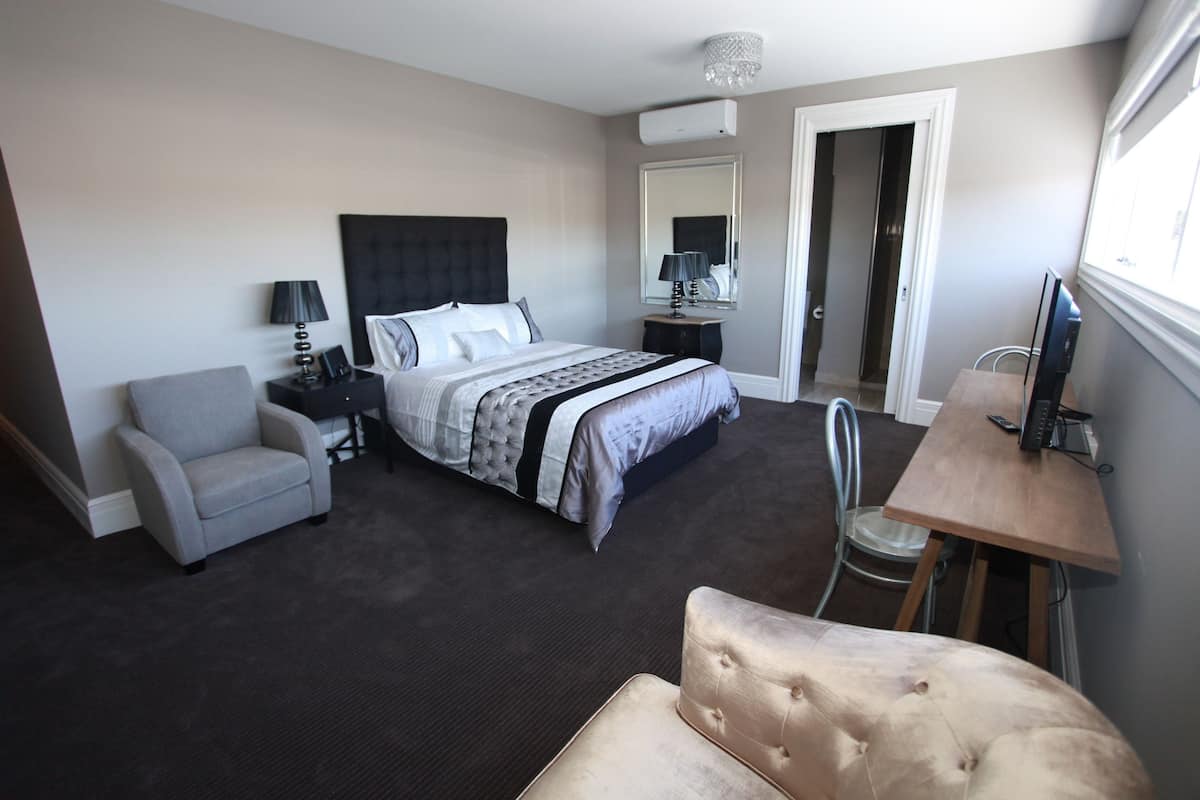 A hotel room with a bed, a desk, a chair, and a sofa.