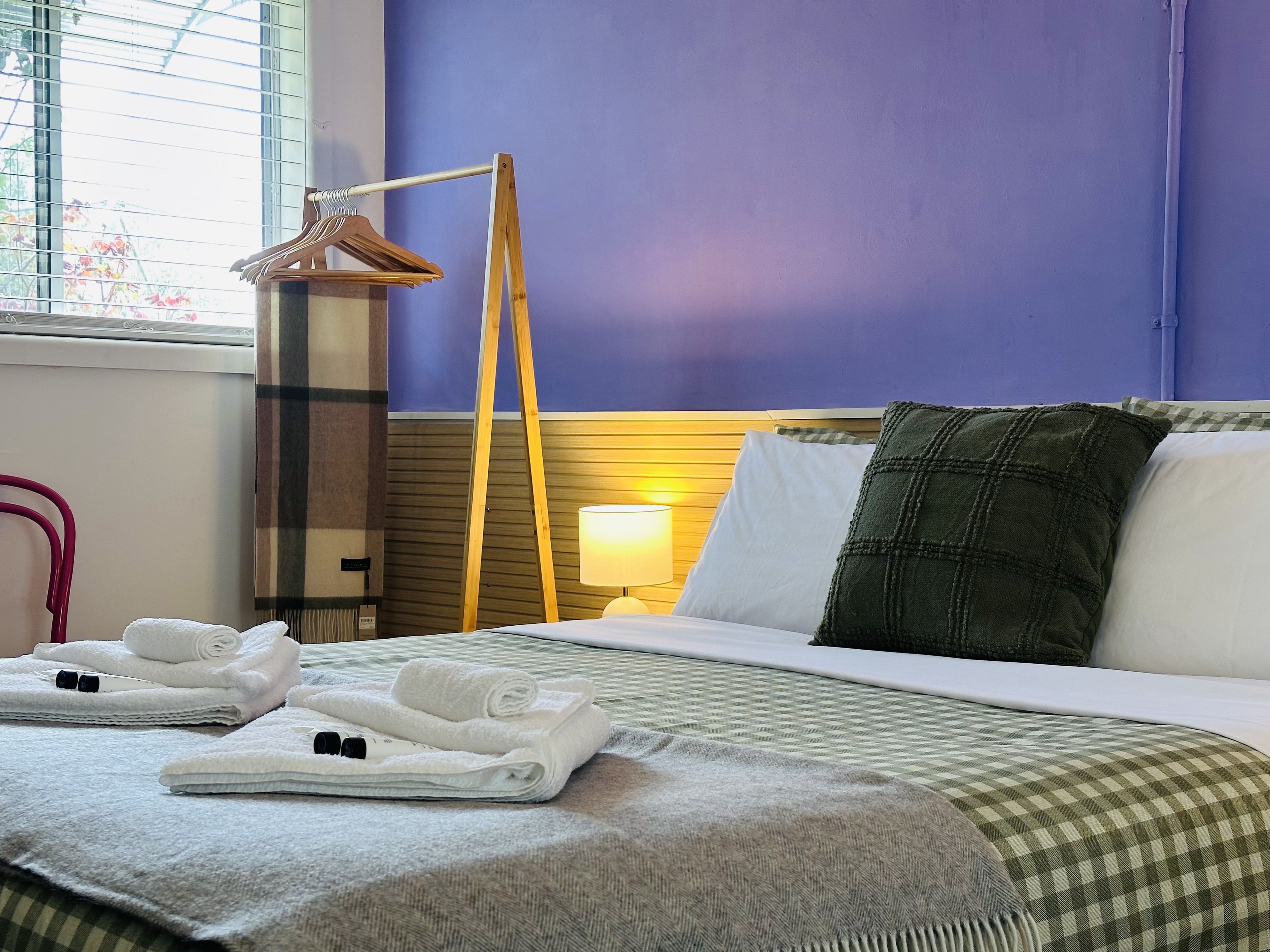 A hotel room with a bed, pillows, a lamp, and towels.
