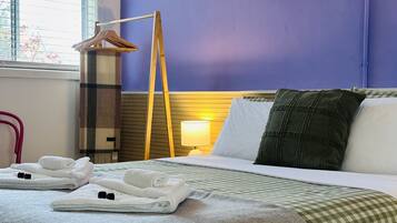 A hotel room with a bed, pillows, a lamp, and towels.