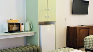 Habitación de hotel con microondas, refrigerador, televisión y cama con colcha a cuadros.