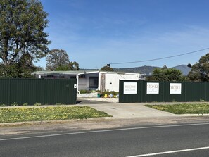 A motel with a green fence, a welcome sign, and a sign for Stonez Motel. - Stonez Boutique Accommodation (Clunes)
