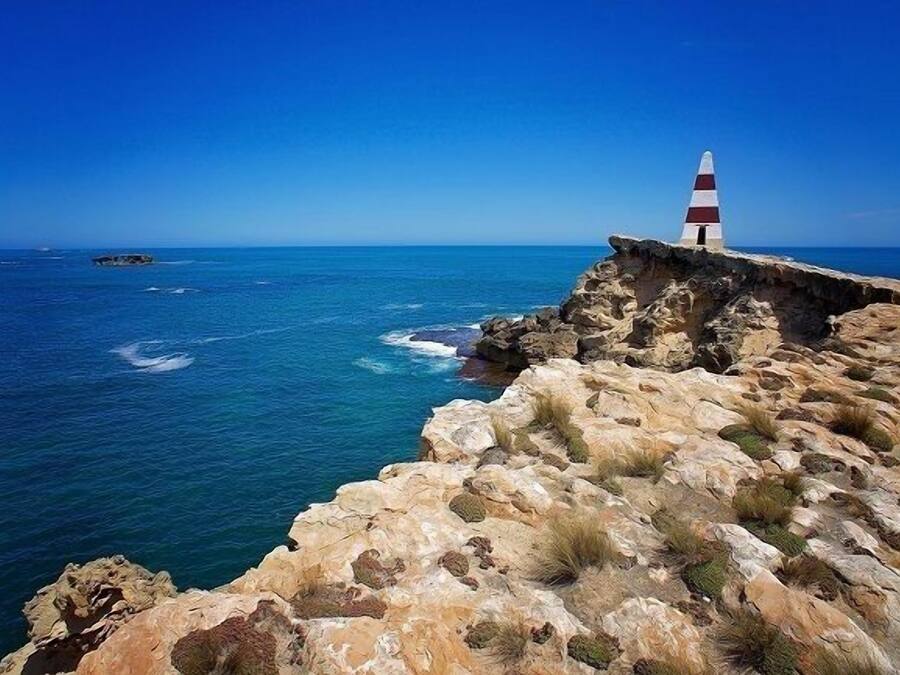 Un paysage côtier avec un phare situé sur un promontoire rocheux.