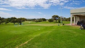 A golf course with a clubhouse, a flag, and a golf cart.