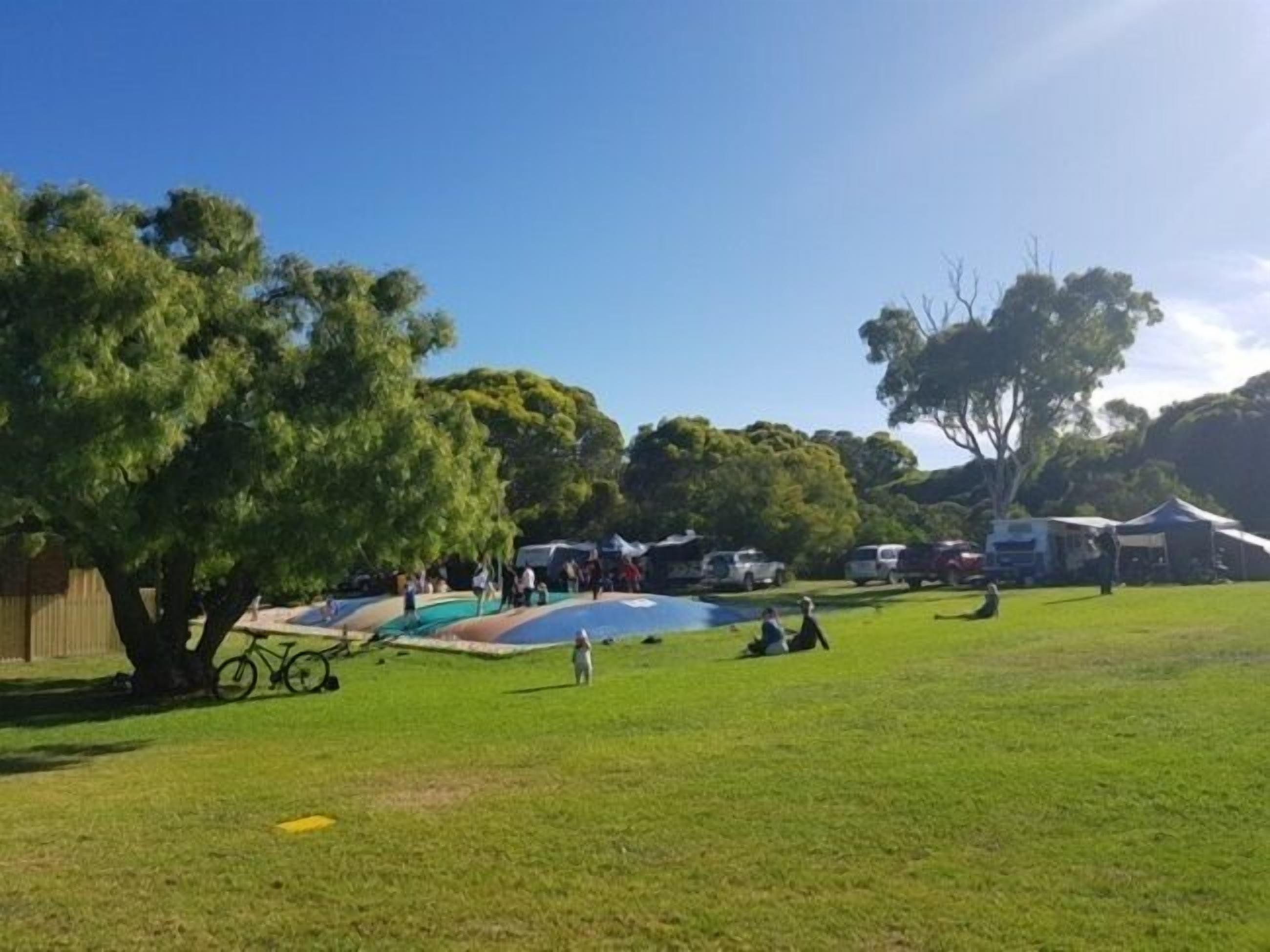 Un espace extérieur verdoyant, avec des arbres, une petite piscine et plusieurs tentes.