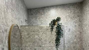 Un baño con un lavamanos blanco, un espejo y una zona de ducha.