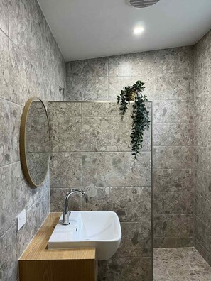 A bathroom with a white sink, a mirror, and a shower area. - Robe Holiday Park (Robe)