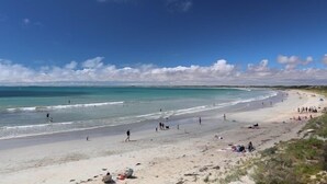 A beach with people walking and sunbathing.