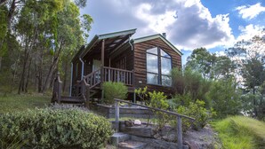 Eine rustikale Holzhütte mit Veranda und einer Treppe zu einer Terrasse.