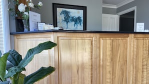 A wooden kitchen counter with a framed painting, a vase with flowers, and a sign indicating AMEX transaction fees.